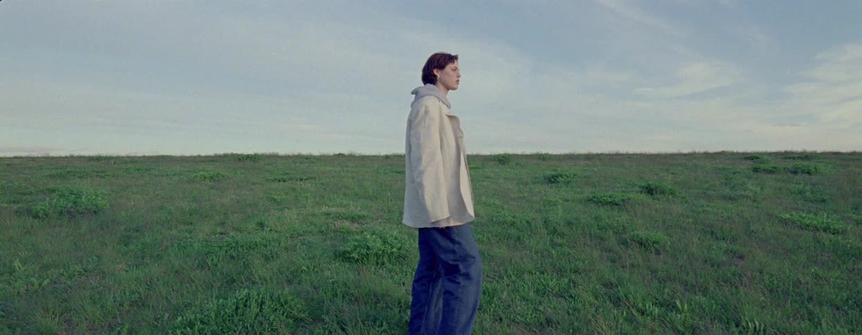 A woman walks through an empty field and then stops looking confused