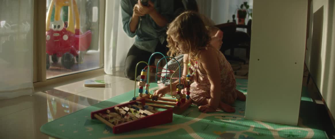 Father filming his daughters playing while sitting with toys