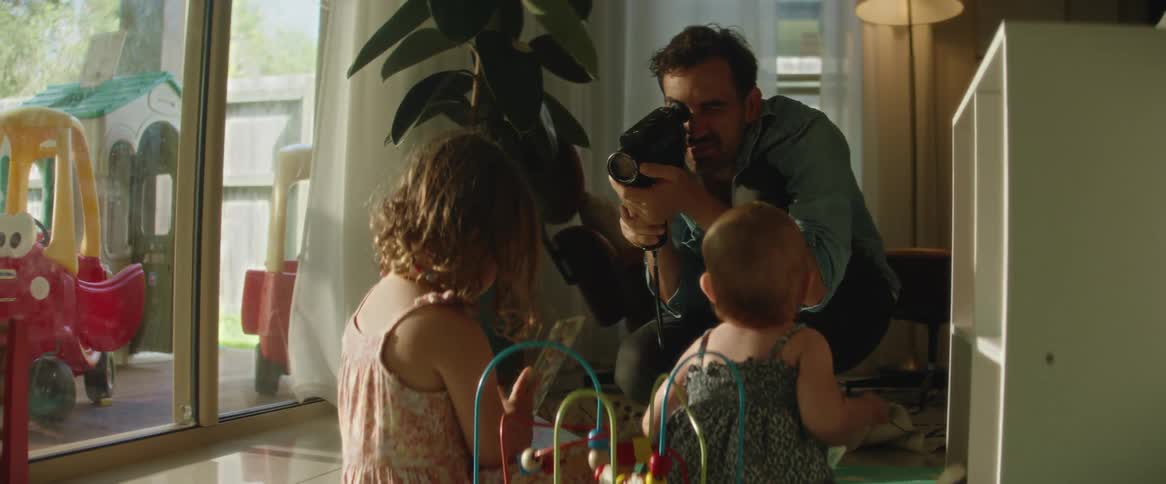 A father films his daughters with a digital video camera
