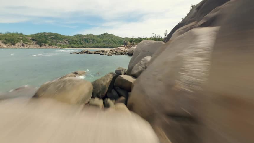 Gliding low over a rocky coast landscape by the sea with an fpv drone
