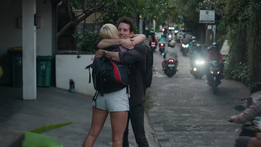 Friends hug as scooters drive by