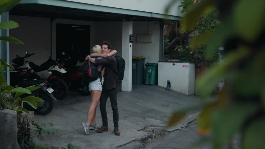 Backpackers hug each other before walking away on a busy road