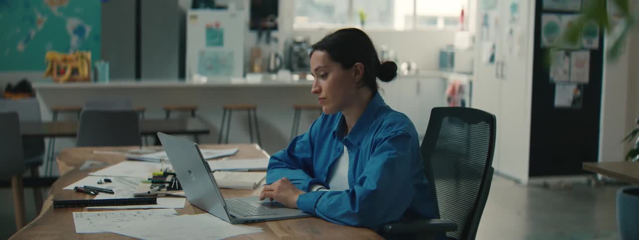 A woman with a prosthesis for her arm sitting on a desk in front of a laptop