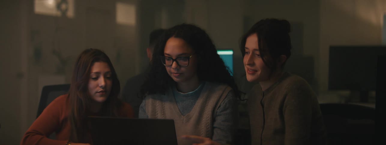Three women sitting in front of a laptop talking