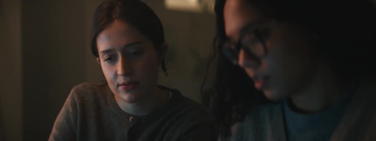 Portrait of two focused women talking to each other in a dimly lit room