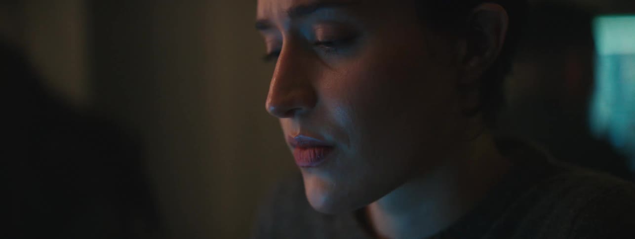 Portrait of a woman sitting in front of a screen in a lowlit room