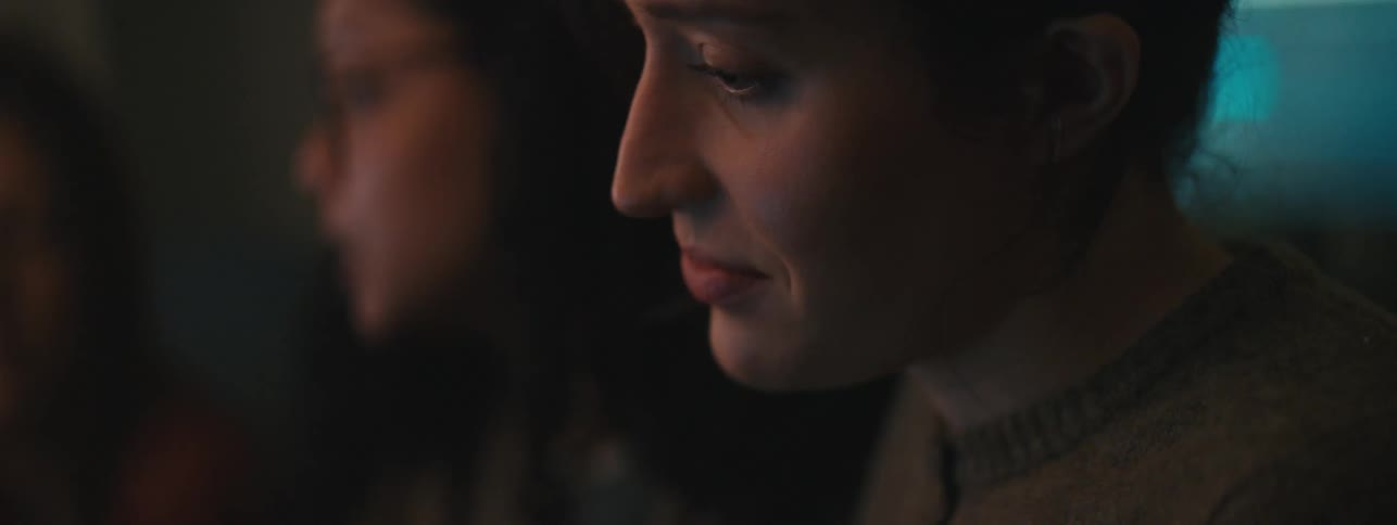 Three women sitting focused on talking in a dimly lit room