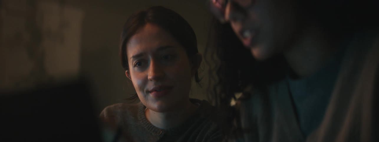 A woman talks to another woman as both stare at a laptop screen