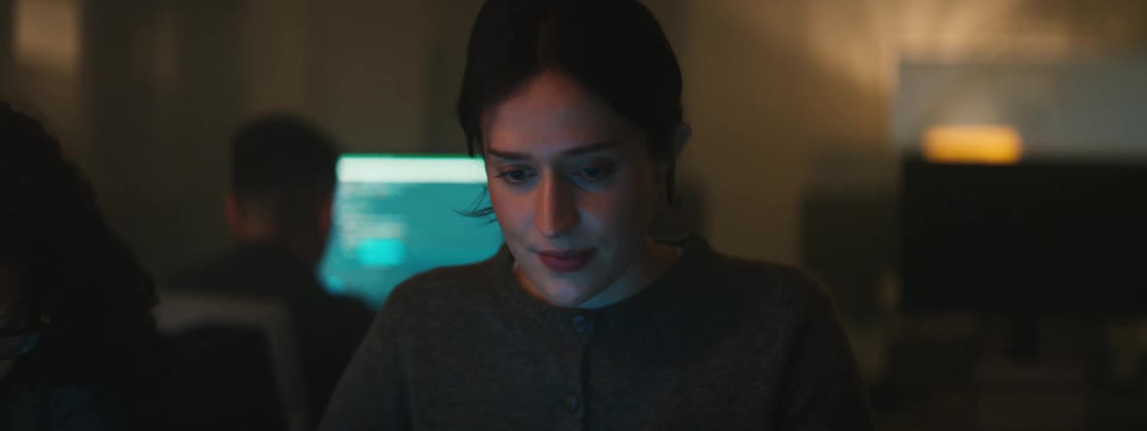 Portrait of a woman sitting in a dimly lit room focused on a screen