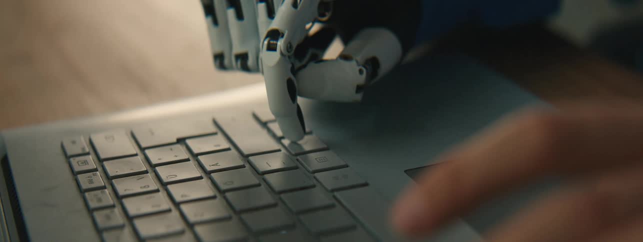 A person with a prosthetic hand taps buttons on a laptop