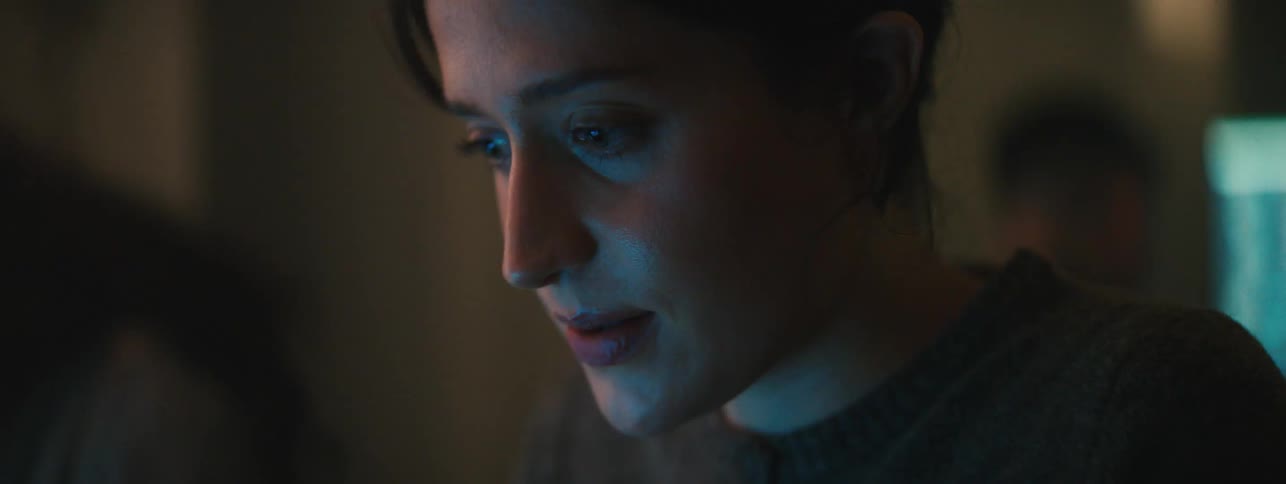 A woman smiles while reading something on a computer screen