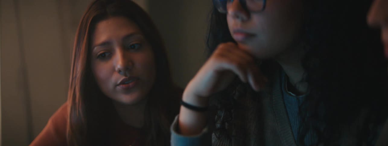 Three friends sitting in a dimly lit room talking