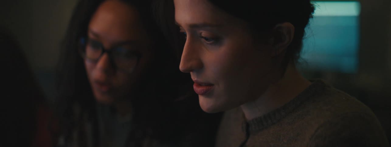Three women sit and talk while looking at a screen
