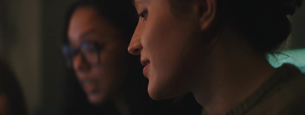 Two women engaged in conversation in a dimly lit office