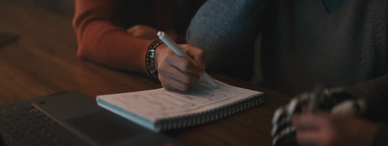 A person writes notes in a notebook