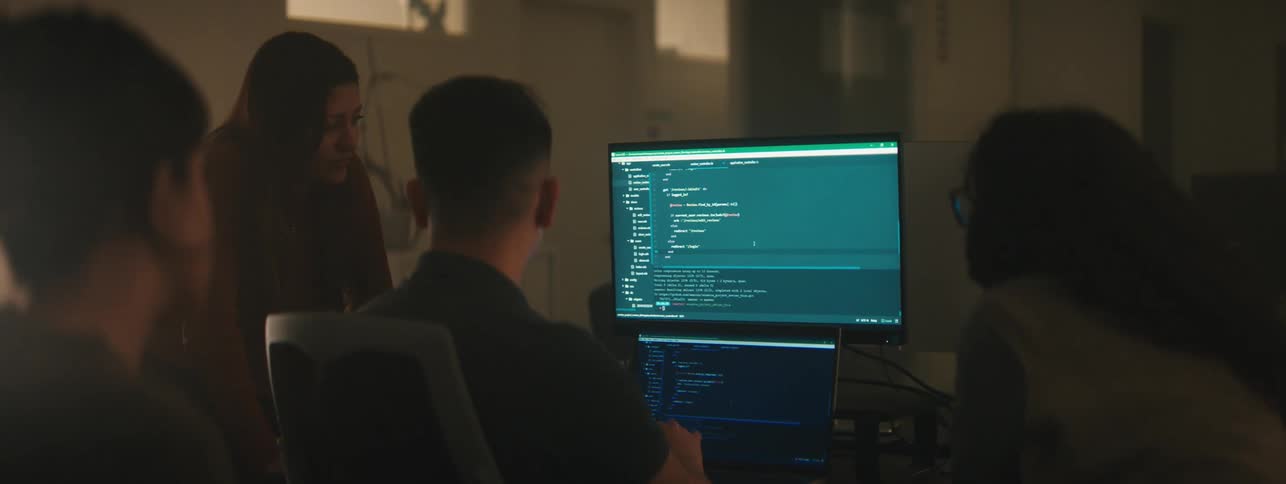 A group of people gathered around computer screens engaged in a coding or programming session