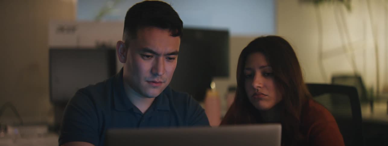 A man and woman look at a laptop and talk