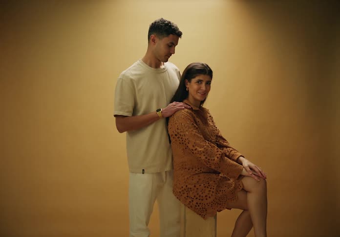 Expectant mother moves her hands while posing with her spouse