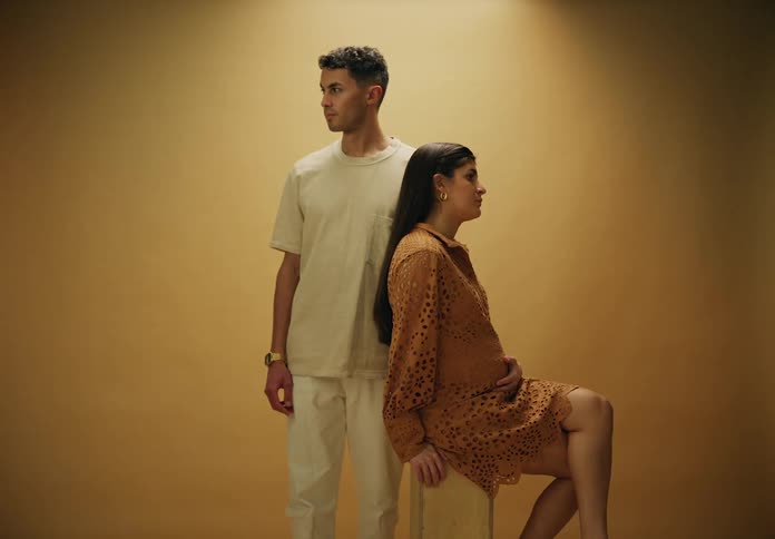 Expectant couple poses against a reddish brown background