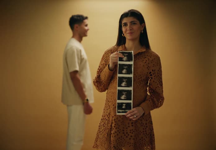 A woman is smiling while she holds ultrasound photos