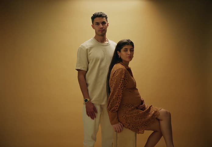 Man standing next to a seated pregnant woman posing in a family photo