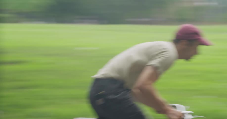 A man on a bicycle speeds by a woman walking dogs in a park