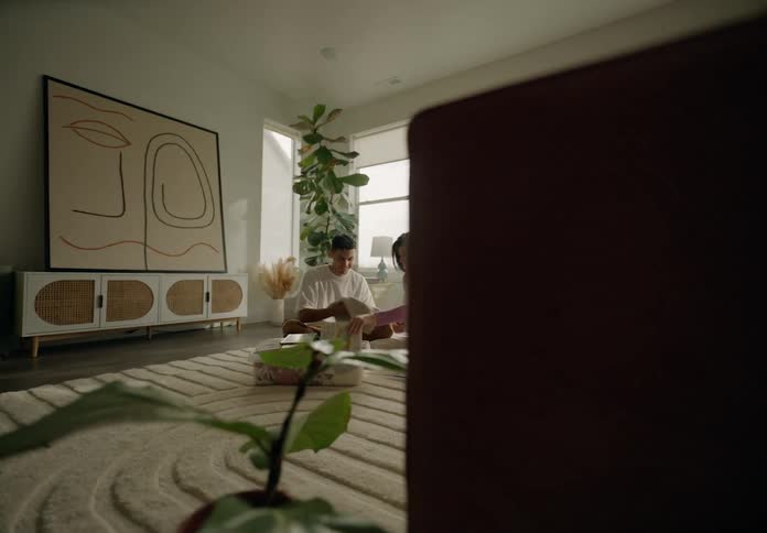 Couple sitting on living room rug looking at clothes and book