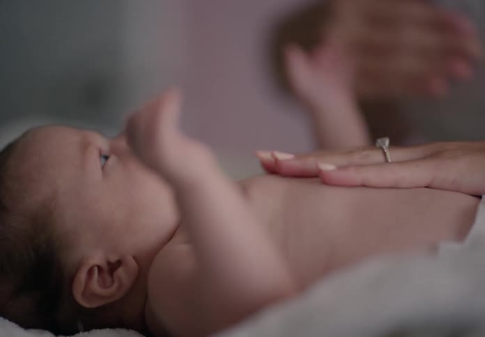 Pair of hands massaging a babys body