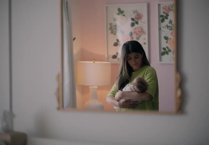 Mother stands and rocks her baby in a room with floral pictures