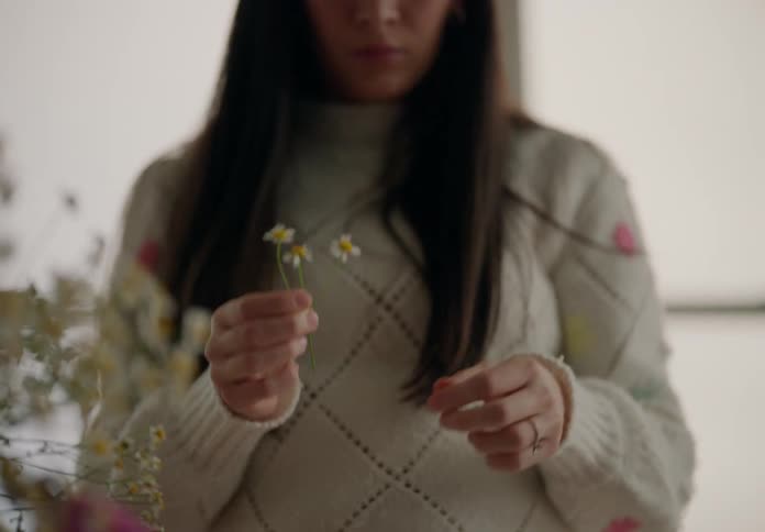 Woman picking a small flower and making a composition on the table