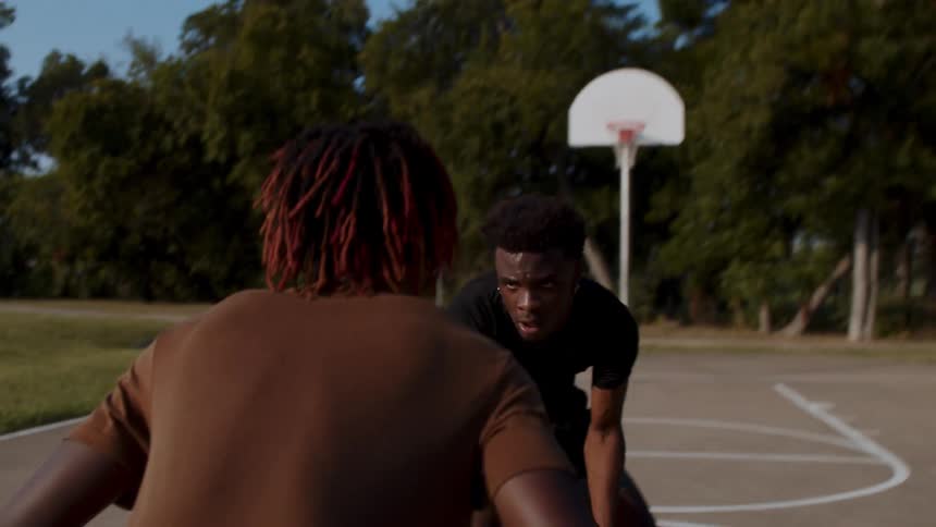 A man takes off his coat and then picks up a basketball and dunks it past an opponent