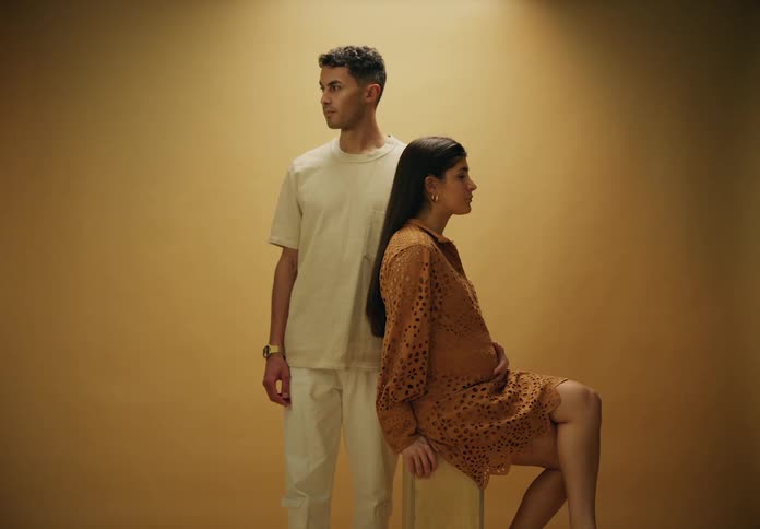 Man standing next to his pregnant wife sitting in a studio