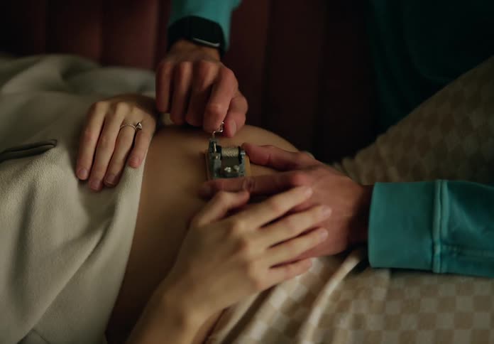 A man is using a device on a pregnant woman