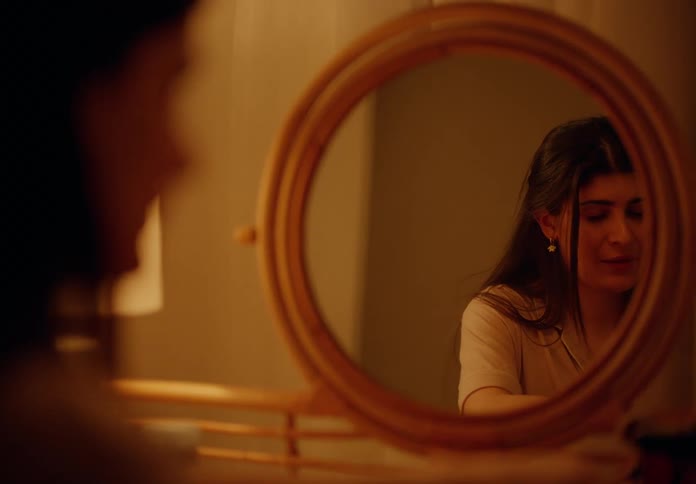 Happy woman sitting in front of a round mirror