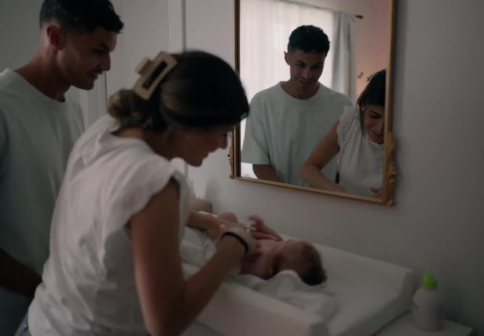 Father and mother applying cream to their newborn baby son