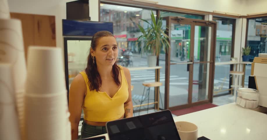 A woman stands in front of a countertop and talks to a restaurant employee