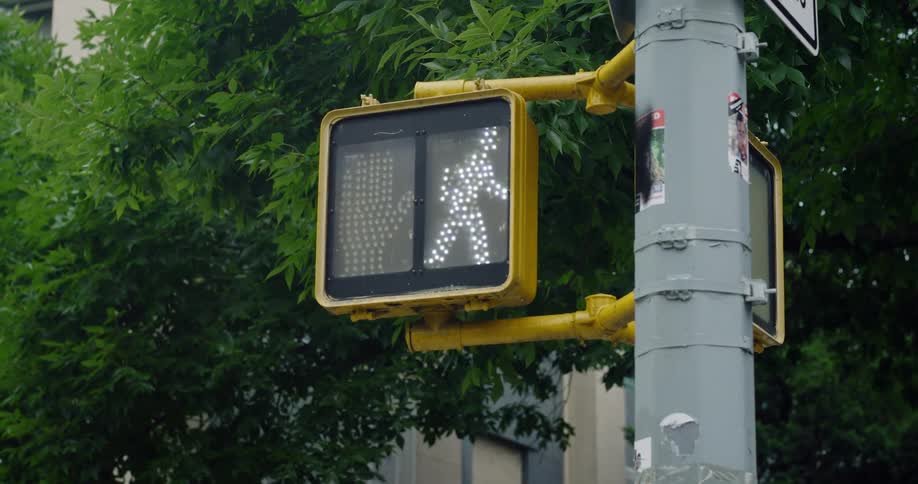 A closeup of a pedestrian crossing sign attached to a grey metal pole