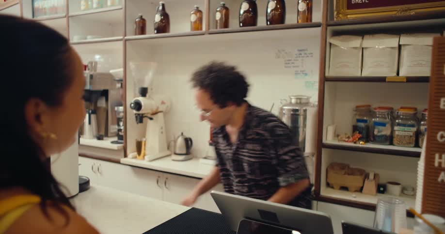 Woman ordering a coffee in a coffeeshop and a man preparing it