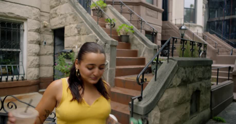 Woman having a drink walking down the stairs with four dogs on a leash
