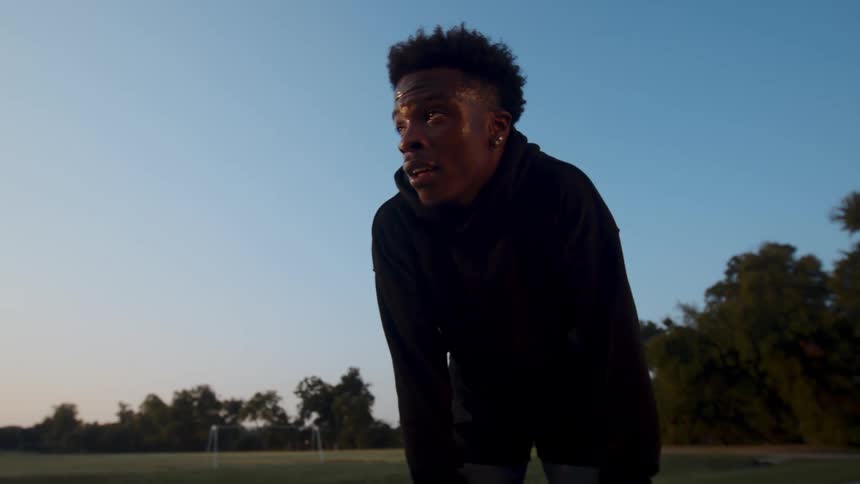 A close up of a young tired man sweating and out of breath on a basketball court outdoors