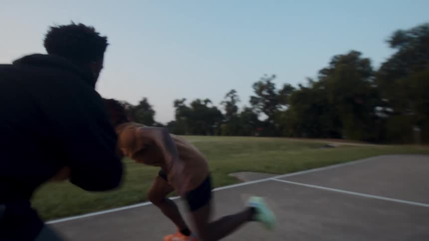 Two young men on a court in the late afternoon playing basketball