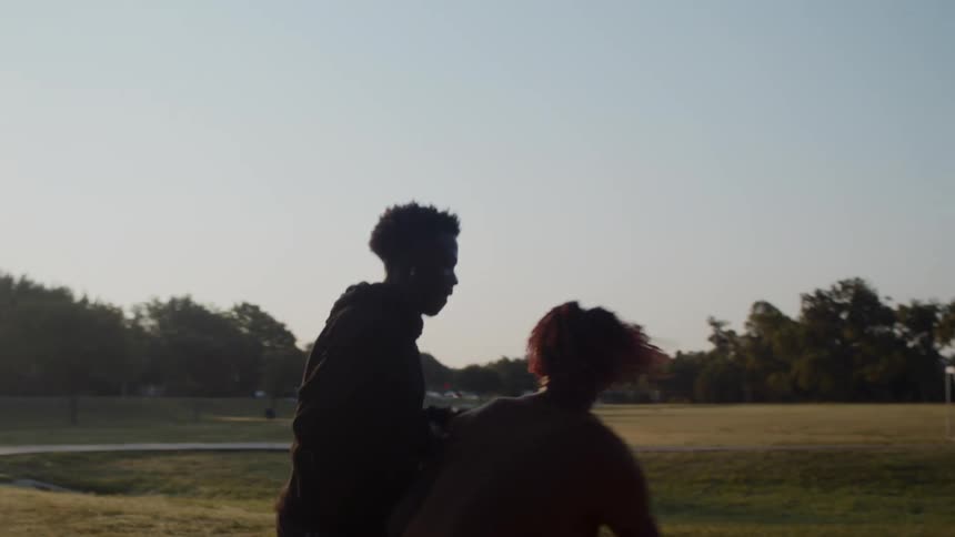 Two male friends play a one on one game of basketball at the park