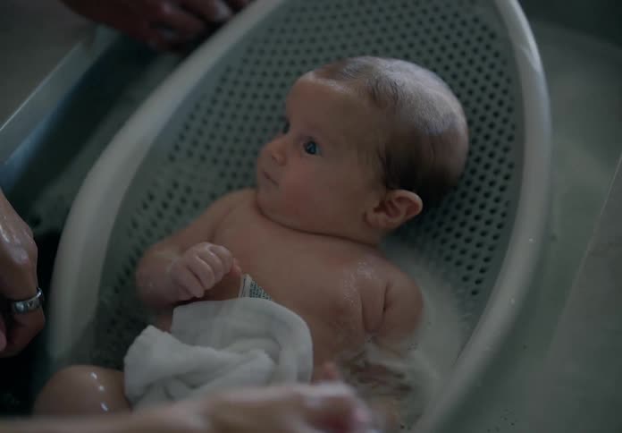 Hands bathing a baby in the sink