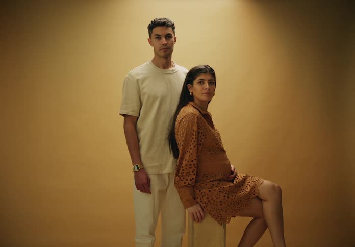 Man and pregnant woman pose in front of a brown wall