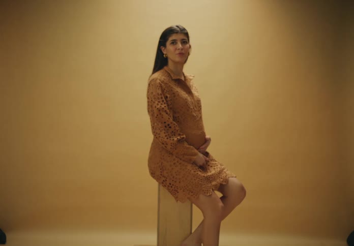 A model is wearing a dress and on a set
