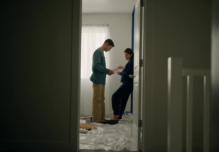 Man and woman face to face in a room holding pictures