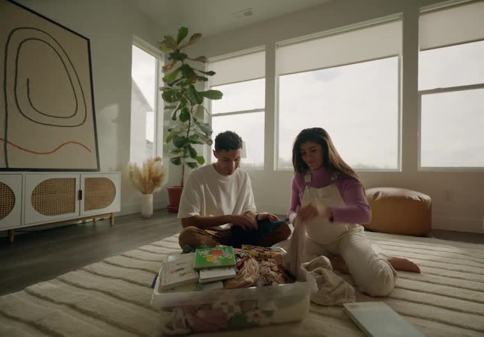 Man next to pregnant woman looking at baby clothes