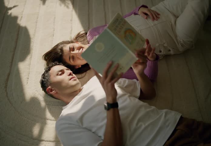 A couple read a book and talk on the carpet