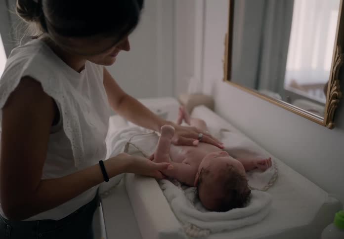Mother applying cream to her newborn baby lying down