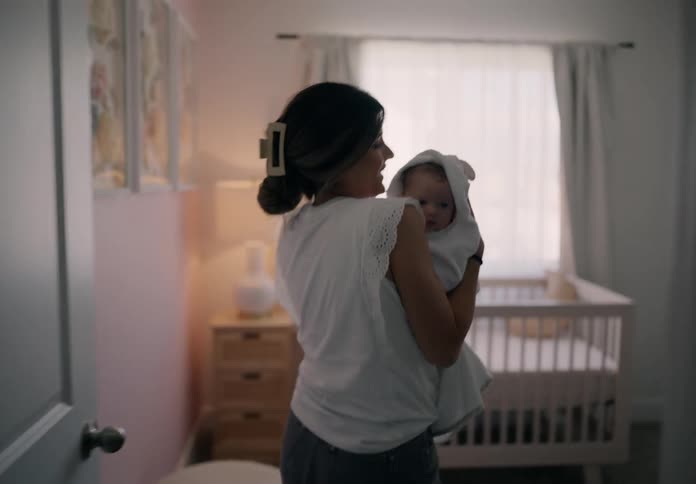 A mother carries her newborn son into the bedroom